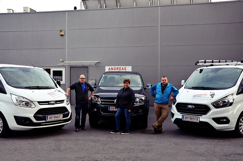 Andreas, Michaela und Rene Teissl vor den Firmenautos und der Halle